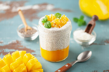 Chia seed pudding from coconut milk with mango puree and cubes  in glass jar. Vegan  food. Clean eating concept