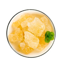 Handmade large grain yellow icing sugar placed in a white bowl with a fresh mint leaf garnish