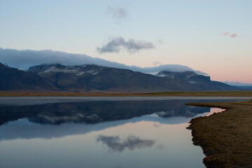 Scenic Nordic countryside with snowy mountain and lake reflection at golden hour in Iceland