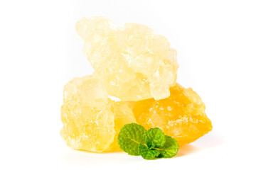 Handmade ancient yellow rock sugar large pieces displayed with fresh mint leaves on a white...