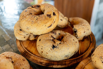 Freshly baked bagels with sesame seeds and olives on a wooden platter in a cozy bakery setting