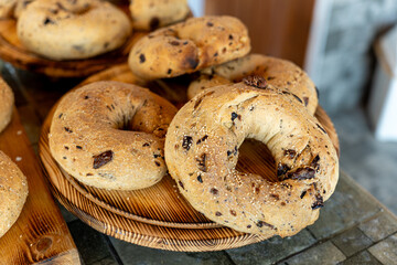 Freshly baked bagels with chocolate chunks displayed on wooden platters at a bakery in the morning light