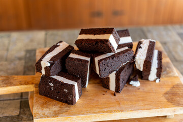 Delicious chocolate ice cream sandwiches stacked on a wooden cutting board in a cozy kitchen setting