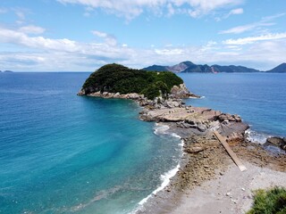 Aerial drone view of Senjojiki on Naru Island, Goto Islands, Nagasaki, Japan – coastal rock terraces, turquoise waters, and lush green landscape under clear summer sky.