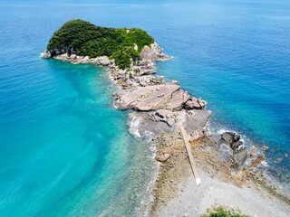 Aerial drone view of Senjojiki on Naru Island, Goto Islands, Nagasaki, Japan – coastal rock terraces, turquoise waters, and lush green landscape under clear summer sky.