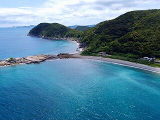 Aerial drone view of Senjojiki on Naru Island, Goto Islands, Nagasaki, Japan – coastal rock terraces, turquoise waters, and lush green landscape under clear summer sky.