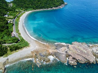 Aerial drone view of Senjojiki on Naru Island, Goto Islands, Nagasaki, Japan – coastal rock terraces, turquoise waters, and lush green landscape under clear summer sky.