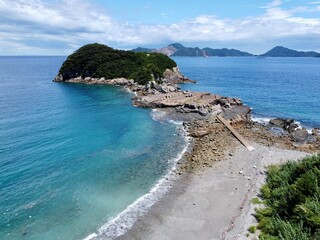 Aerial drone view of Senjojiki on Naru Island, Goto Islands, Nagasaki, Japan – coastal rock terraces, turquoise waters, and lush green landscape under clear summer sky.