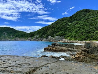 Aerial drone view of Senjojiki on Naru Island, Goto Islands, Nagasaki, Japan – coastal rock terraces, turquoise waters, and lush green landscape under clear summer sky.