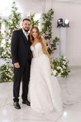 Naklejka premium The bride and groom embrace affectionately in a room decorated with many flowers