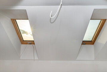 Attic with roof windows finished to a shell state, walls covered with plaster.