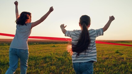 Little girls running to finish line. Kids girls running to finish line in sun rays in park. Victory success. Active children running. Sport, child champion. Girl winner. Happy child running on lawn