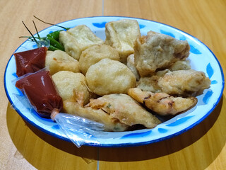 Gorengan, traditional Indonesian street food consisting of brontak tofu, fried banana, bakwan, jemblem, etc. Served with green chilies.