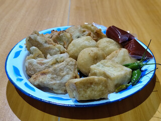 Gorengan, traditional Indonesian street food consisting of brontak tofu, fried banana, bakwan, jemblem, etc. Served with green chilies.