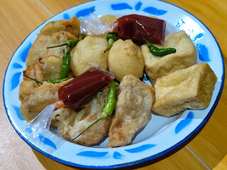 Gorengan, traditional Indonesian street food consisting of brontak tofu, fried banana, bakwan, jemblem, etc. Served with green chilies.