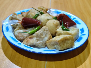 Gorengan, traditional Indonesian street food consisting of brontak tofu, fried banana, bakwan, jemblem, etc. Served with green chilies.