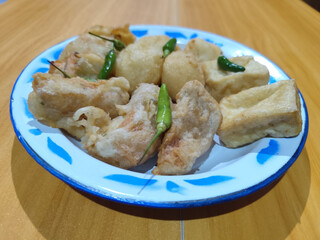 Gorengan, traditional Indonesian street food consisting of brontak tofu, fried banana, bakwan, jemblem, etc. Served with green chilies.