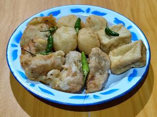 Gorengan, traditional Indonesian street food consisting of brontak tofu, fried banana, bakwan, jemblem, etc. Served with green chilies.