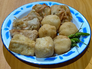 Gorengan, traditional Indonesian street food consisting of brontak tofu, fried banana, bakwan, jemblem, etc. Served with green chilies.