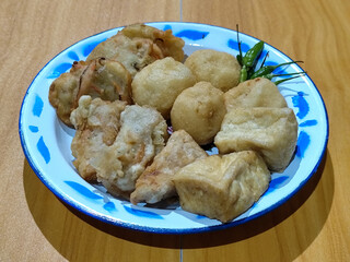 Gorengan, traditional Indonesian street food consisting of brontak tofu, fried banana, bakwan, jemblem, etc. Served with green chilies.