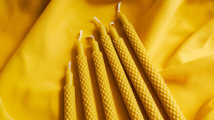 Aesthetic arrangement of natural beeswax candles on a yellow background