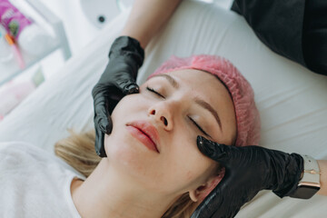 young woman getting professional face massage at aesthetic clinic