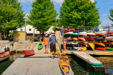 healthy active senior lifestyle: man (sun hat, sun glasses, grey beard,) cleaning a sea kayak on a...