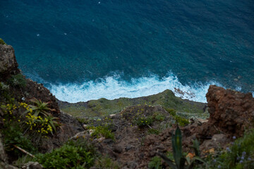 High cliff view of deep blue ocean with crashing white waves and rocky coast below, featuring...