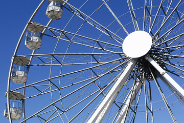 Ferris wheel closeup with blue sky. Metal structure of amusement ride. Empty gondolas in daylight....
