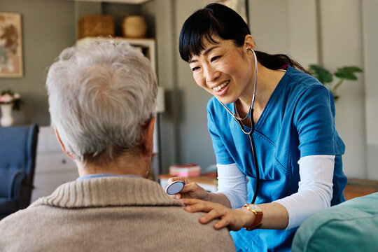 Doctor or nurse caregiver with senior man at home or nursing home using a stethoscope during an exam