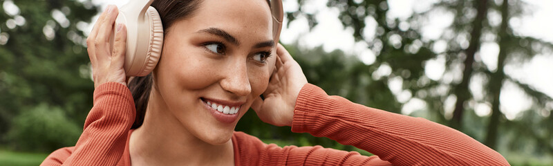 Joyful yoga teacher enjoys music while practicing outdoors in serene environment