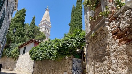 Stone alleyway with church tower view in old Croatian town