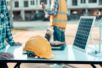 Hard hat pointing at solar panels on desk. Energy worker with clipboard. Checking solar panel...