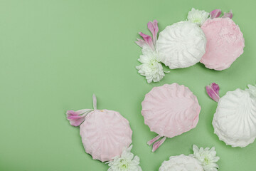 Fruit marshmallow with fresh flower petals on pastel green background. Lactose free vegan dessert