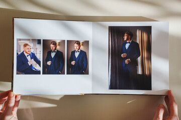 Female hands flipping through a photo book with wedding photos on a white table