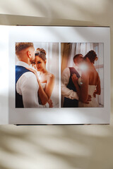 page of an open photo book with wedding photos on a white table