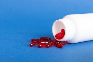 Red pills spilled around a pill bottle. Medicines and prescription pills flat lay background. Red medical capsules