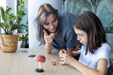 Female mentor and schoolgirl assembling anatomical brain model together. Concept of STEM education, biology learning, neuroscience and interactive teaching.