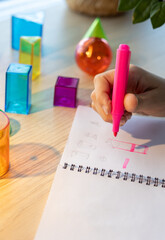 Two schoolgirls studying 3D geometric shapes during math class, drawing and discussing figures...