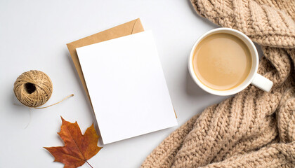 Cozy Autumn Still Life: A charming composition features a warm cup of coffee, an autumnal leaf, a knitted scarf, and a blank card, invoking feelings of comfort and seasonal ambiance.