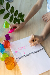 Two schoolgirls studying 3D geometric shapes during math class, drawing and discussing figures...