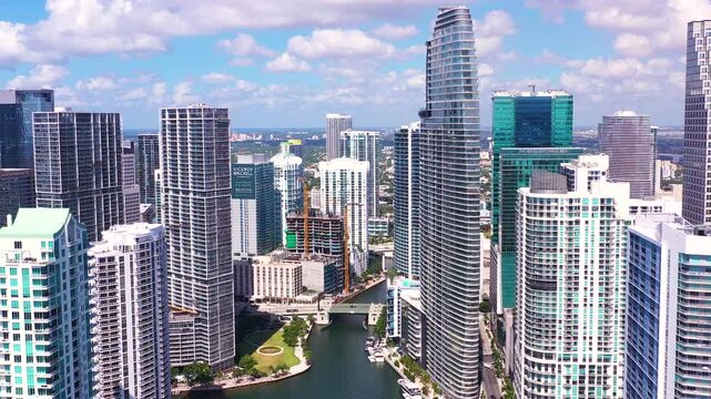 4K Aerial Footage of Downtown Miami Skyline and Miami River, Condos, Towers, and Sunny Urban Cityscape slow pull back. 