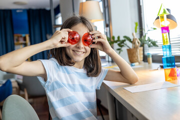 Happy girl covering her face with a green geometric ball, enjoying a fun and playful moment while...