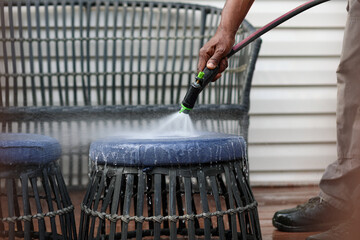 A Black Man Power Washing A Wooden Deck