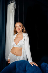 Obraz premium bride with long hair in white silk pajamas in a room with a wedding dress.