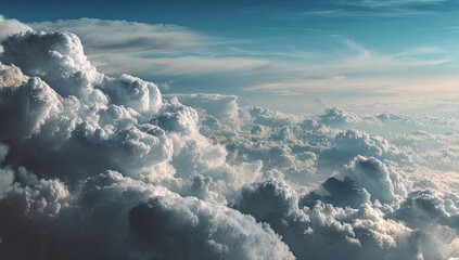 A vast expanse of cumulus clouds, seen from high above. Massive, puffy clouds of varying shades of gray and white fill the frame, stretching to the horizon.