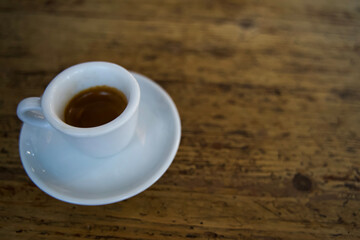 Blurred photo of Espresso coffee in a white cup on a rustic wooden table with natural light...