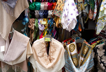 Colorful display of various scarves and shawls hanging in a vibrant market stall with rich textures...