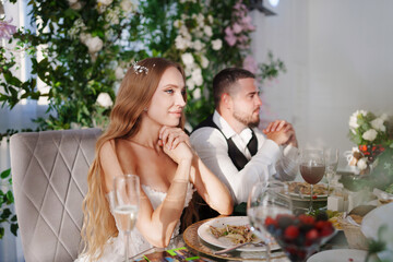 The bride and groom at the newlyweds' table, decorated with many flowers. 
