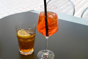 Verre de spritz et verre de thé glacé sur une table